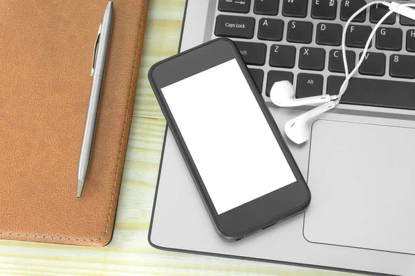 Office table with,flower note book pen ,smartphone and other supplies. Blank smartphone page for input the text in the middle. Top view, flat lay.