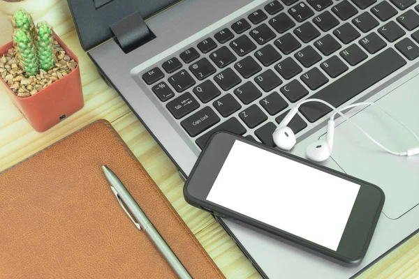 Office table with,flower note book pen ,smartphone and other supplies. Blank smartphone page for input the text in the middle. Top view, flat lay.