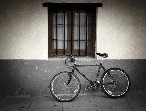 Bicicleta apoiada em uma parede perto de uma janela com barras — Fotografia de Stock