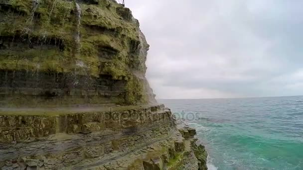 Vattenfall som faller från en klippa och havet surf — Stockvideo