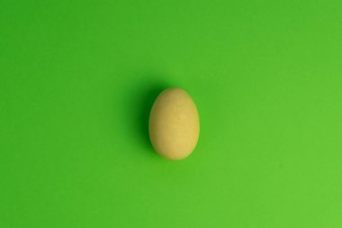 Yeşil arka planda izole edilmiş sarı bir Paskalya yumurtası. En küçük, en üst görünüm.