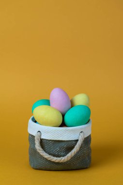 Seramik sepet konseptli renkli paskalya yumurtaları. Kopyalama alanı ve turuncu arkaplan ile görüntüle.