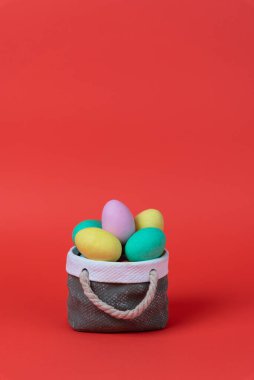 Seramik sepet konseptli renkli paskalya yumurtaları. Kopyalama alanı ile görüntüle, kırmızı arkaplan.