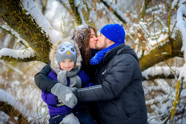 happy family poses under a tree in the winter wood