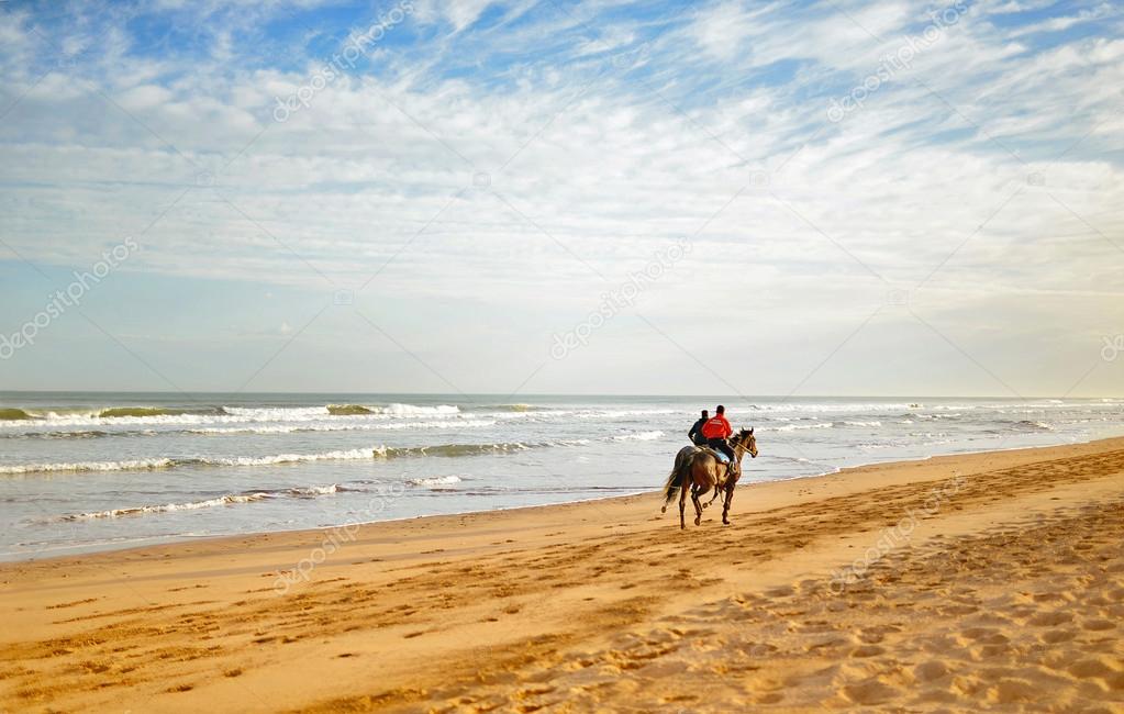 two riders jumping astride on the beach