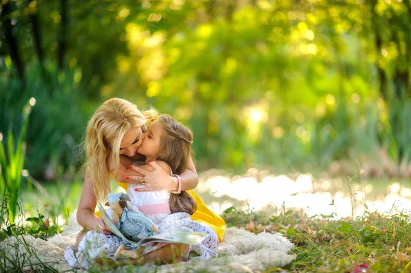 Moeder leest het boek in de dochter op een gras — Stockfoto