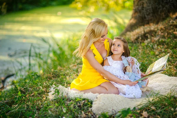 Anya szól a könyv, a lánya a fűben — Stock Fotó