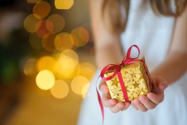 çocuk yavaşça elinde bir Noel hediyesi tutar.