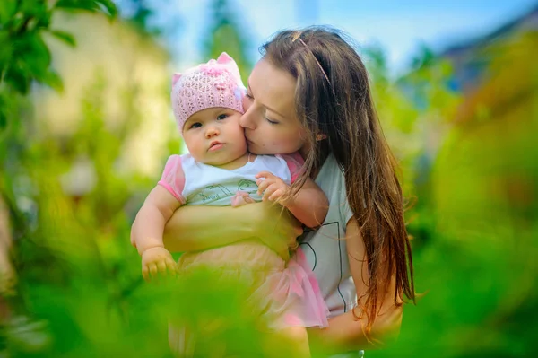 mutlu anne güneşli bir günde parkta çocukla birlikte yürür, çocuğu kucaklar ve öper