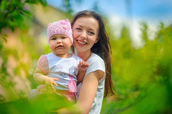mutlu anne güneşli bir günde parkta çocukla birlikte yürür, kucaklar ve gülümsüyor