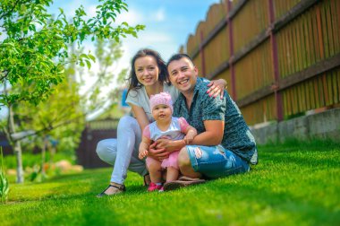 mutlu aile evin yakınındaki bir çim üzerinde oynar, kucaklamak ve gülümseme