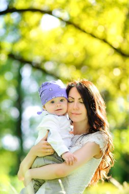 güneşli bir gün, kucaklama ve gülümseme mutlu anne parkta çocuk ile yürüyor
