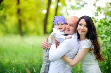 Aile güzel parkta bir günbatımı üzerinde yürür, dostça kucaklamak ve gülmek