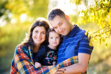 Günbatımında bir sonbahar Park'ta yürüyordunuz, yastıklı bir kucaklama gizleme ve gülümseyerek mutlu bir aile