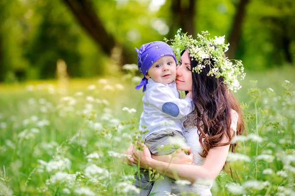 妈妈带着心爱的婴儿在公园散步 她妈妈的头上有一束野花 — 图库照片