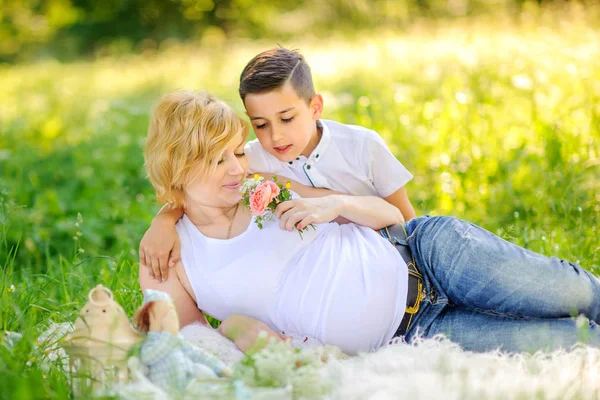 Niño Dio Flores Gentilmente Abraza Amada Madre Sentada Hierba Parque —  Fotos de Stock