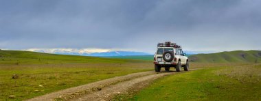 yol dağlarında mesafe bir karlı zirveleri, yolda bir off-road araç görebilirsiniz