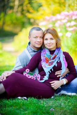 akşam parkta geziniyor, çim üzerinde oturan ve smilin aşık Çift