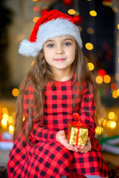 Linda Menina Santa Claus Chapéu Senta Chão Com Presente Mãos — Fotografia de Stock