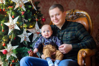 şenlikli bir Noel ağacının yanında oturan bebek mutlu baba