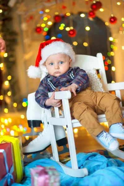 Ein Kleines Lustiges Kind Mit Weihnachtsmannmütze Sitzt Auf Einem Stuhl — Stockfoto