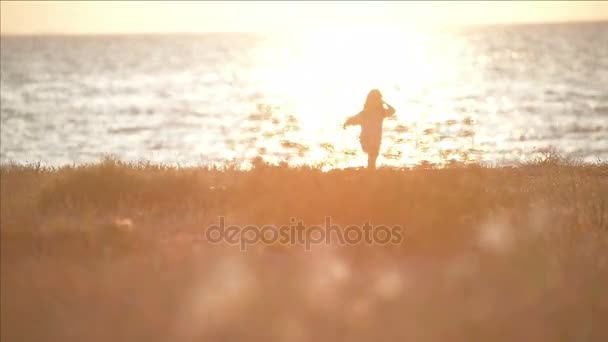 小さな女の子はソフト フォーカス エーゲ海の海岸に夕日を歩く — ストック動画
