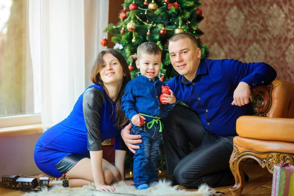 お祝いクリスマス ツリー近くの床に坐っている幸せな家族と贈り物を楽しんで — ストック写真