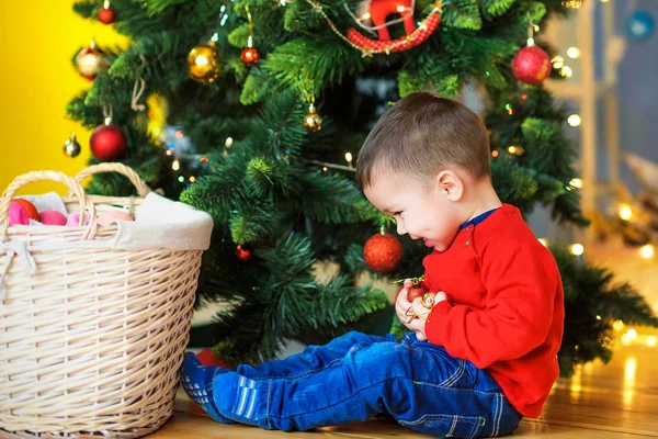 Glückliches Kind Das Auf Dem Festlichen Weihnachtsbaum Sitzt Spielt Und — Stockfoto