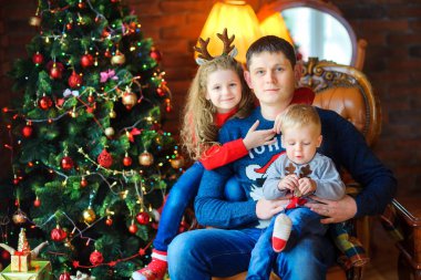 Baba sevdiklerinize şenlikli ağaç yakın bir sandalyede yavaşça kucaklama ve SMIL oturmak