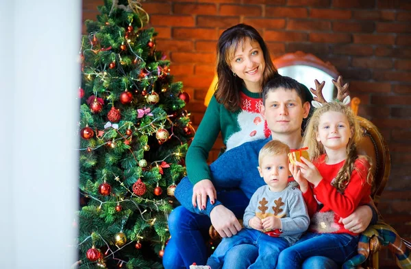 お祝いクリスマス ツリー 椅子に座っていると Embracin に近い部屋で幸せな家族 — ストック写真