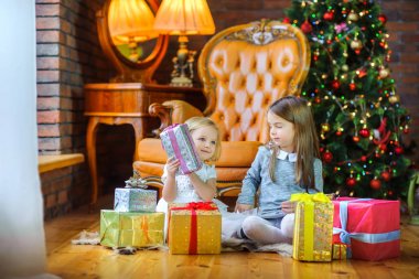 Noel sabahı, iki kız kardeş şenlikli bir Noel tre yakın katta oturan hediyeler açın.