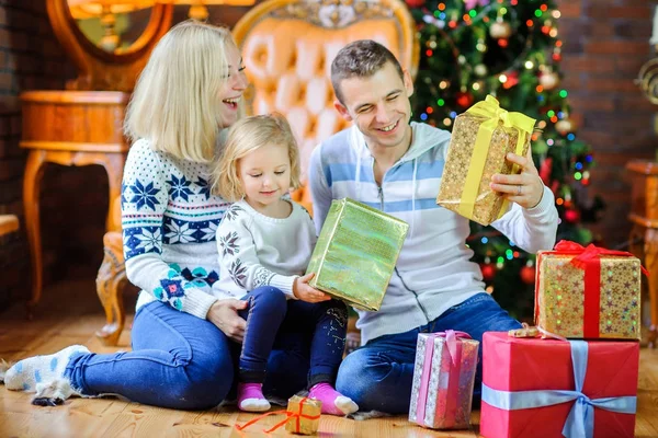クリスマス ツリー近くの床に坐っている幸せな家族 お互いのプレゼントを渡して — ストック写真