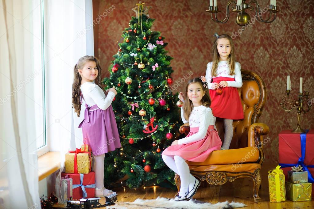 Three sisters decorate the Christmas tree with ball