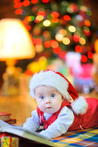Ein Lustiges Kind Mit Weihnachtsmannmütze Liegt Auf Dem Boden Neben — Stockfoto