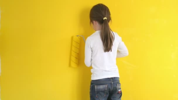 面白い少女は恐る恐る部屋にローラーで壁を塗料します — ストック動画