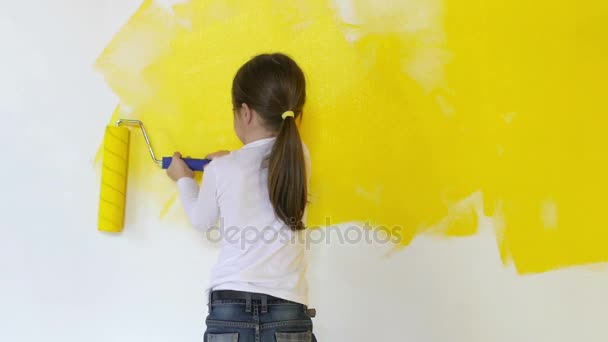 面白い少女は恐る恐る部屋にローラーで壁を塗料します — ストック動画