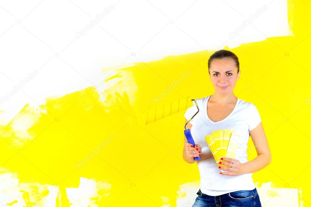 girl painter holds a roller in his hands and chooses a color for painting the walls, on the wall inscription repai