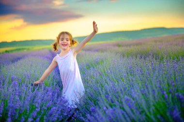 güzel küçük bir kız yürüyüş ve having fun lavanta sahada günbatımında