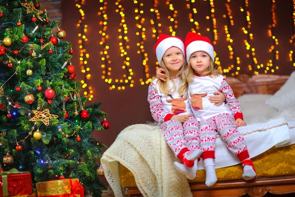 Duas Meninas Bonitinhas Pijama Chapéus Papai Noel Estão Sentados Cama — Fotografia de Stock