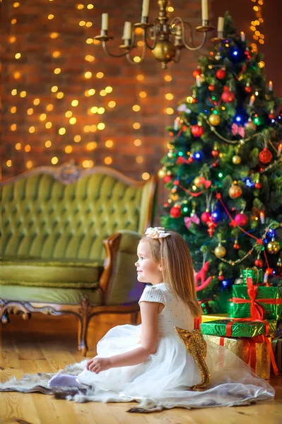 Roztomilá Dívka Bílých Šatech Sedí Podlaze Blízkosti Slavnostního Vánočního Stromečku — Stock fotografie