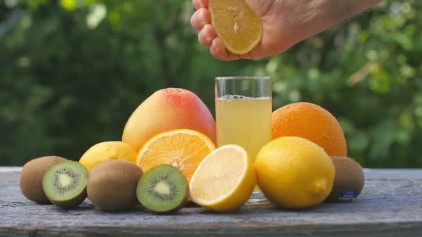 Manlig Hand Pressar Saft Från Frukter Till Ett Glas Bland — Stockvideo