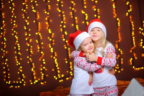 Duas Irmãs Bonitinhas Bonés Papai Noel Estão Abraçando Enquanto Estão — Fotografia de Stock