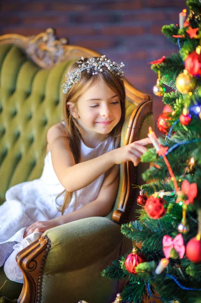 Cute Little Girl Sits Sofa Festive Christmas Tree Touches Considers — Stock Photo, Image