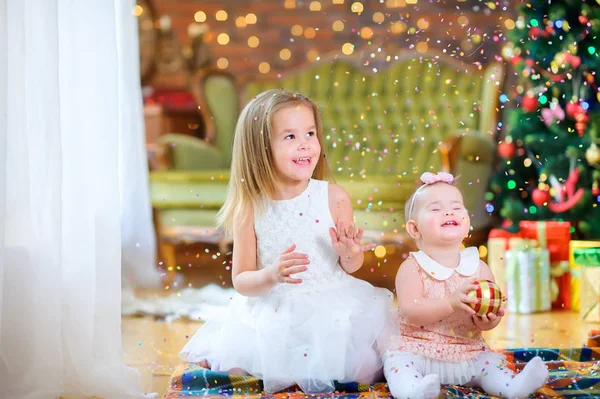 Dvě Roztomilé Holčičky Elegantních Šatech Sedí Podlaze Pozadí Slavnostního Vánočního — Stock fotografie