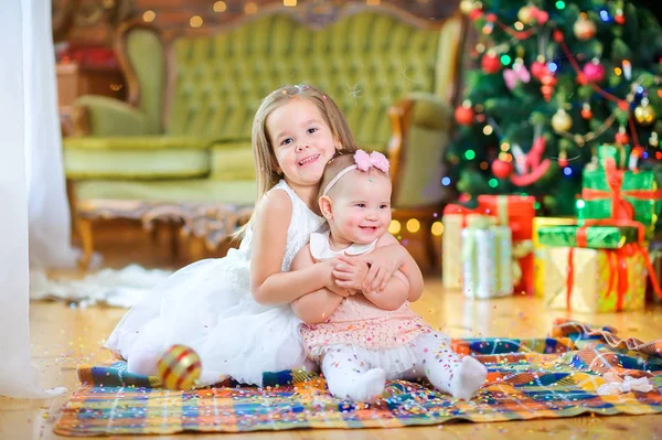 Dvě Roztomilé Holčičky Elegantních Šatech Sedí Podlaze Pozadí Slavnostního Vánočního — Stock fotografie