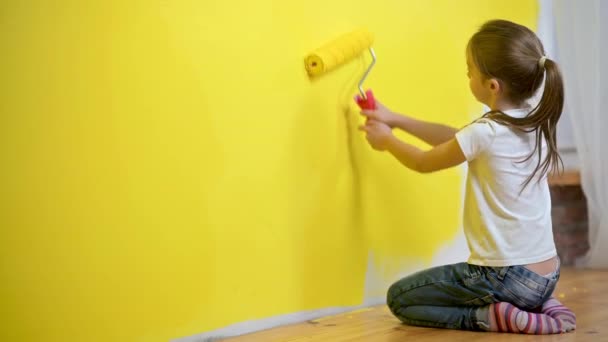 Little girl paints a wall by roller in the room. Children help around the house. Repair in the house. — Stock Footage Little Girl Paints Wall Roller Room Children Help House Repair Stock Video