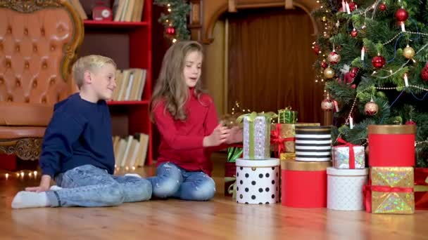 Дети Дарят Подарки Сидя Полу Возле Елки Обнимаются Веселятся Рождество — стоковое видео