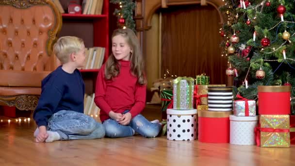 Kinder Beschenken Sich Auf Dem Boden Neben Dem Weihnachtsbaum Sitzend — Stockvideo