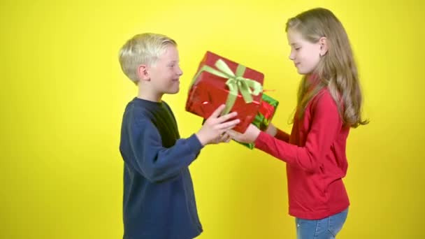 Leuke Kinderen Geven Elkaar Cadeautjes Knuffelen Elkaar Een Gele Studioachtergrond — Stockvideo