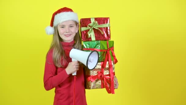 Девушка Шляпе Санта Клауса Коробками Руке Кричит Мегафон Жёлтом Фоне — стоковое видео